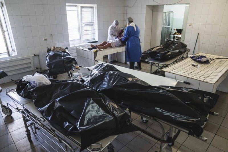 كادران صحيان يجهزان جثة متوفَّى بكوفيد بمستشفى خارج كييف. (وكالات)