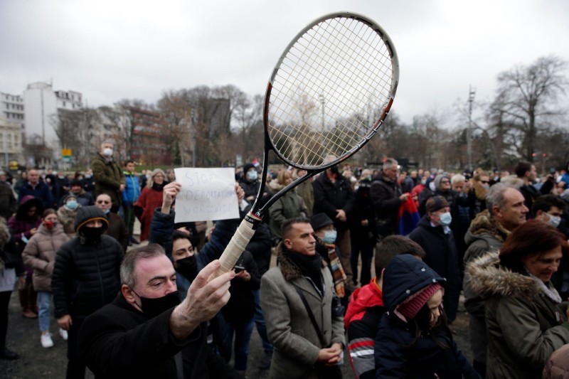 مشجع يلوح بمضرب تنس خلال احتجاج جماهيري في بلغراد، صربيا، بعد الإعلان عن منع النجم الصربي ديوكوفيتش من دخول أستراليا. (EPA)