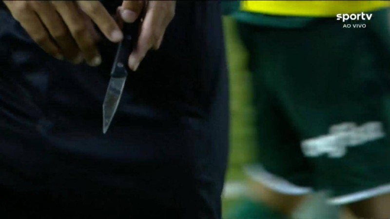 حكم المباراة لحظة ضبطه السكين على العشب بعد اقتحام مشجعي ساوباولو أرض الملعب.