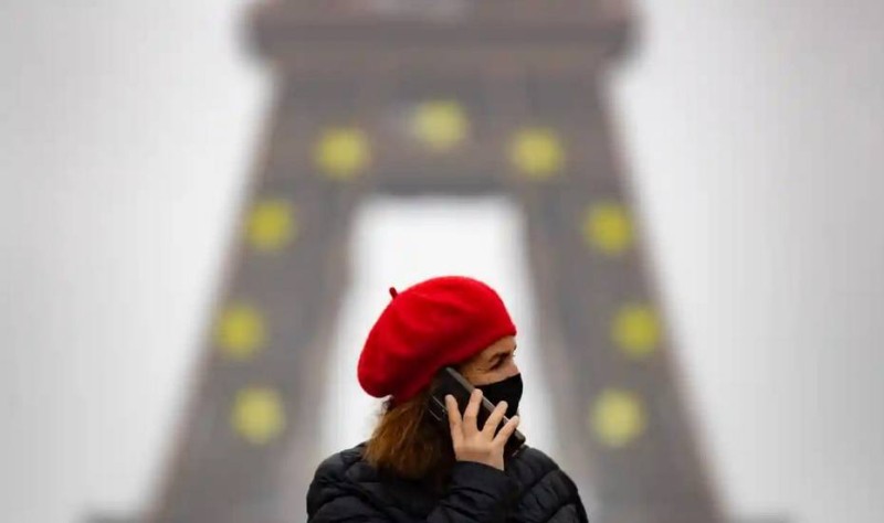 فرنسية تحمي نفسها بالكمامة، ويبدو خلفها برج إيفل في باريس. (وكالات)