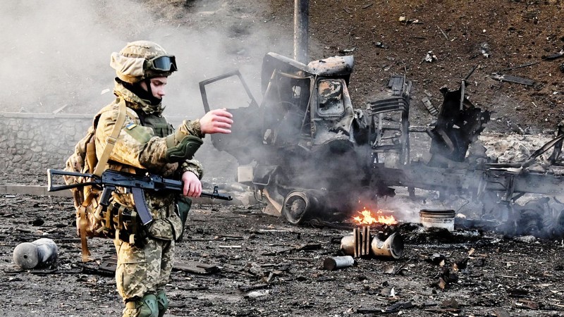 



جندي أوكراني يقف أمام سيارة مدمرة.