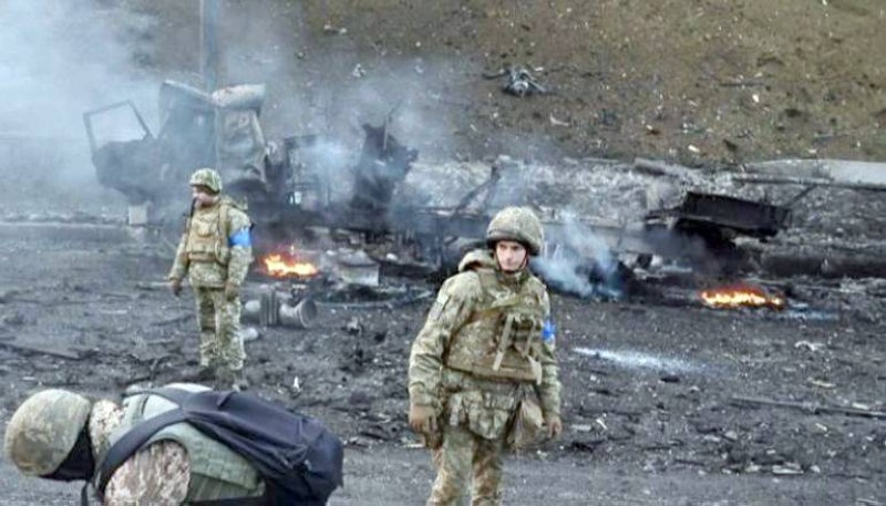 جنود أوكرانيون بجوار آليات عسكرية محترقة .