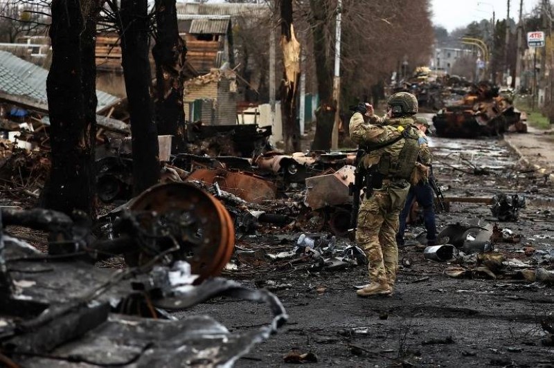 جندي أوكراني يصور بهاتفه المحمول دبابات روسية مدمرة ببلدة بوتشا قرب كييف.