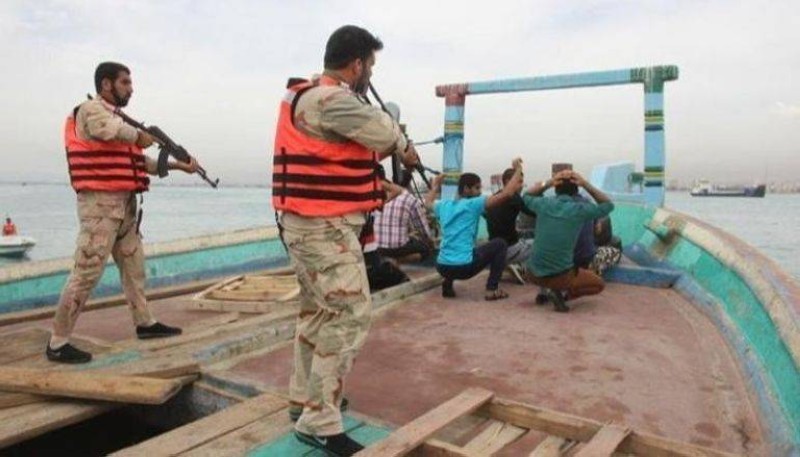 عنصران من الحرس الثوري الإيراني خلال عملية توقيف طاقم سفينة بزعم التهريب.