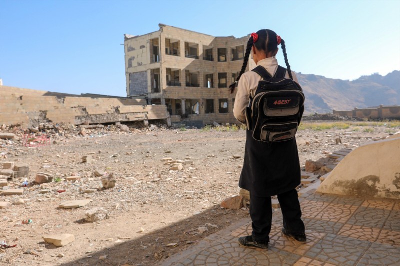 طفلة يمنية تراقب مدرستها التي دمرتها المليشيا في محافظة تعز