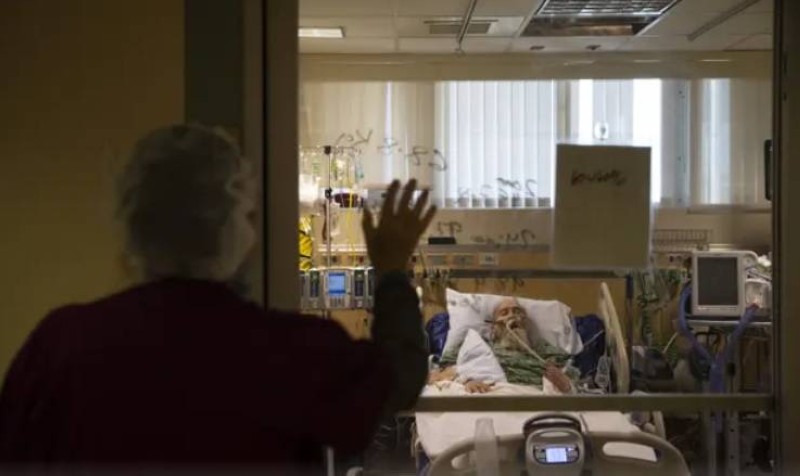 أمريكية تزور مسناً عبر نافذة زجاجية في دار للرعاية في كاليفورنيا. (وكالات) 