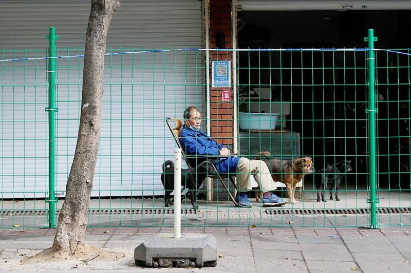 



مسن صيني يجلس خلف السور الذي يعني إغلاق مجمعه السكني. (وكالات)