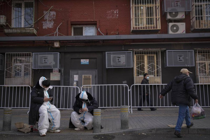 حارسان يرتديان الزي الواقي يحرسان بوابة تغلق مبنى سكنياً في بكين. (وكالات) 