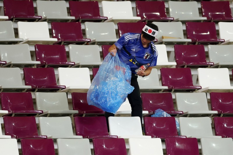 مشجع ياباني يحمع القمامة من المدرجات خلال مباراة ألمانيا واليابان في استاد خليفة الدولي.  