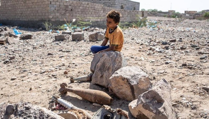 أطفل يمني يقف بجوار ضخائر والغام حوثية غير متفجرة