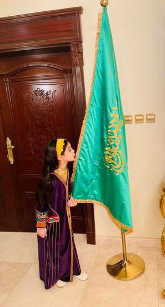 طفلة تطبع قبلة على العلم السعودي 
