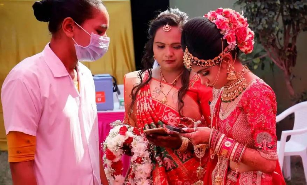



عروس هندية تعرض شهادة تطعيمها على مفتشة صحية داهمت قاعة الفرح خلال 2022. (وكالات)