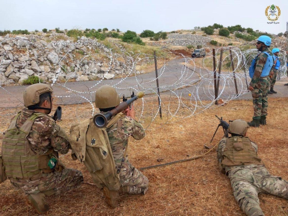 جنود لبنانيون يصوبون أسلحتهم نحو جنود إسرائيليين على خط الحدود.