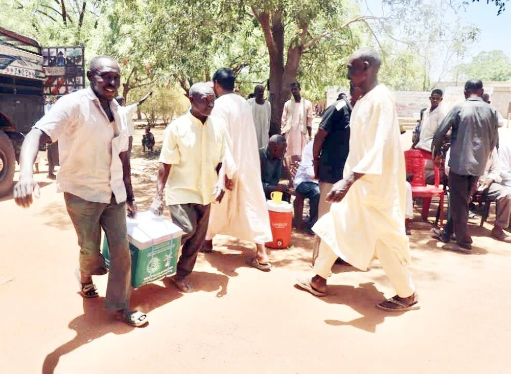 



مواطنون سودانيون يحملون المساعدات التي قدمت لهم. (واس)